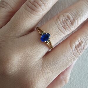 Gold ring with a central oval blue sapphire and diamond-like accents